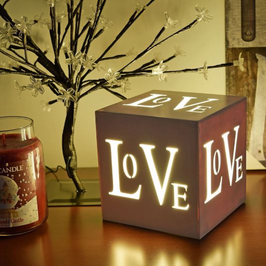Foto de um quadrado com interior iluminado e todas as extremidades com aberturas que formam a palavra "Love". 