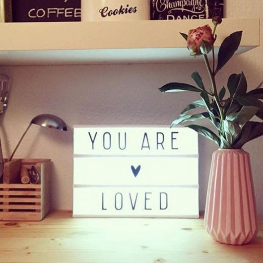 Foto de uma luminária em formato quadrangular com os dizeres "You Are Loved"