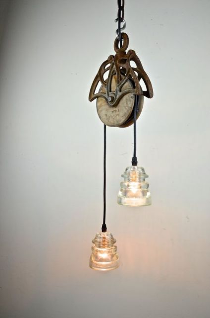 Foto de duas lâmpadas, cada uma de uma lado de uma roldana pendurada no teto. 