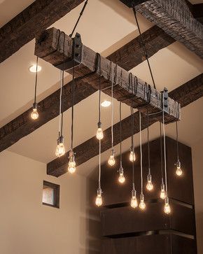 Foto de diversas lâmpadas penduradas em um tronco de madeira suspenso no teto. 
