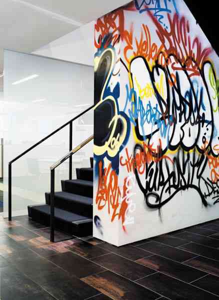 Foto de uma parede grafitada que fica ao lado de uma escada. 