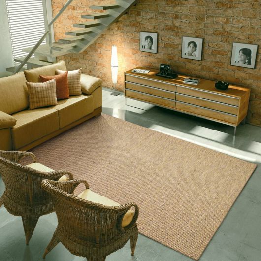 Sala com sofá amarelo, poltronas de madeira e tapete sisal grande.
