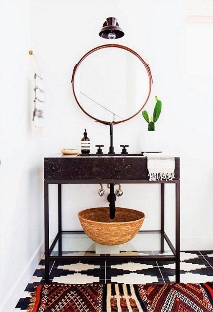 Banheiro com espelho redondo, vaso e cesto de vime.