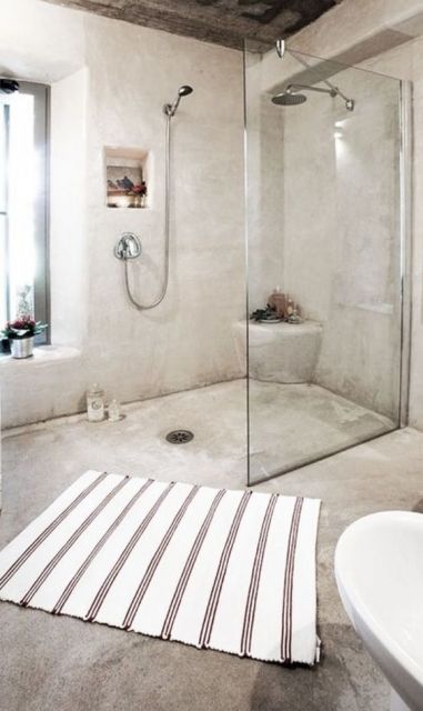 Banheiro com paredes e piso de cimento.