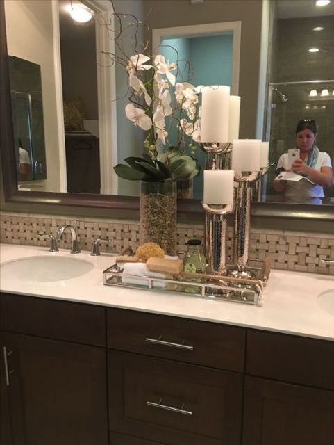Banheiro com bandeja na pia, velas e flores.