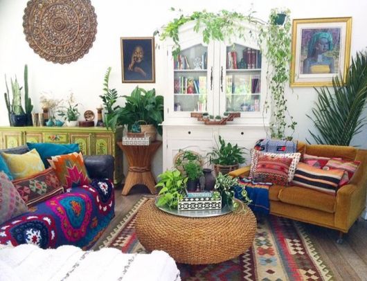 Mesa em palha para apartamento pequeno com decorações coloridas e muitas plantas em volta