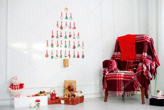 árvore de natal de parede em sala com poltrona vermelha.