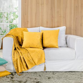 Sofá branco com manta amarela.