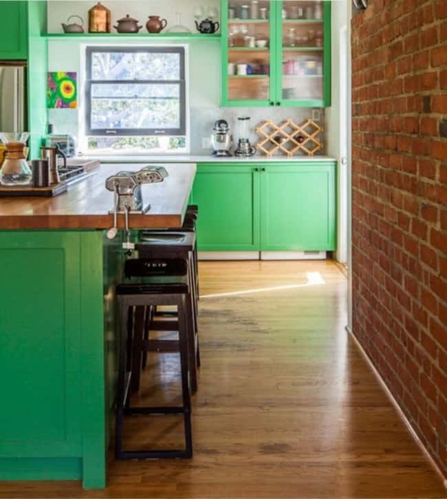Cozinha verde com tijolos à vista