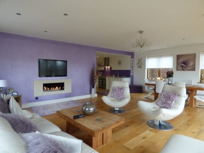 sala grande com parede lilás e sofá branco