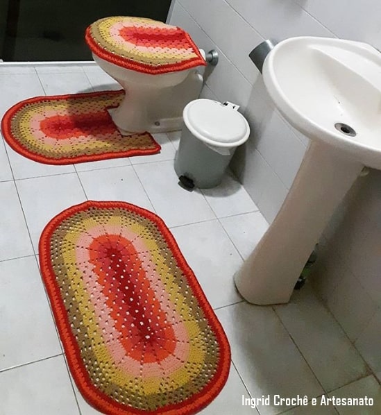 banheiro com conjunto de tapetes de crochê coloridos