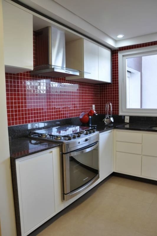 cozinha com armários brancos e parede de pastilhas vermelhas