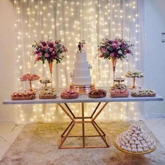 decoração de festa com cortina de led com tecido atrás da mesa do bolo