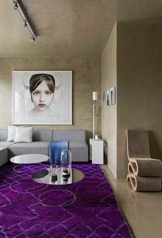sala com tapete violeta e paredes de cimento queimado