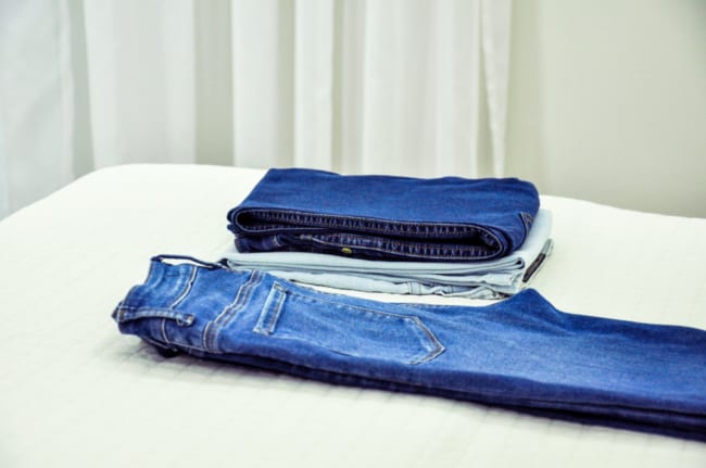 calcas jeans dobradas e esticadas em cima da cama